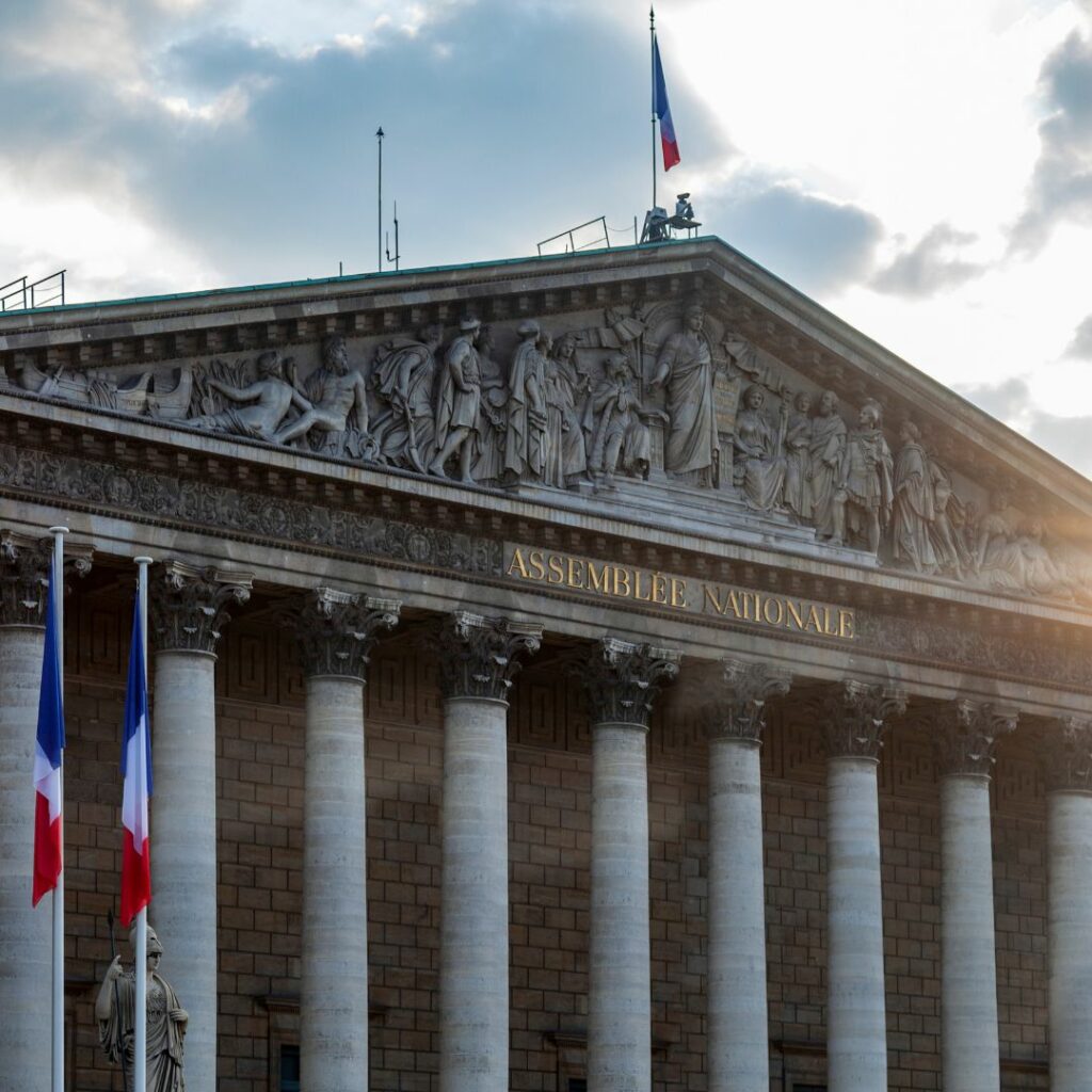 Facade de l'Assemblée nationale, à Paris. Avec deux drapeaux français bleu blanc rouge. Et le ciel avec des nuages et une belle luminosité.